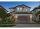Charming two-story home at dusk featuring a manicured lawn, brick driveway, two-car garage, and attractive architectural details at 9811 Aurea Moss Ln, Orlando, FL 32832