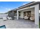 Covered outdoor patio area showcases wicker chairs and a dining set with modern pavers and a partial view of the pool at 9811 Aurea Moss Ln, Orlando, FL 32832