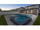Backyard features a swimming pool, jacuzzi, patio and lounging area with nice fencing at dusk at 9811 Aurea Moss Ln, Orlando, FL 32832