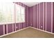 Unique bedroom featuring vertical striped paint, neutral carpet, and bright natural light from shuttered windows at 1027 Banks Rose St, Celebration, FL 34747