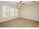 Spacious bedroom with neutral carpet, ceiling fan, and bright natural light from three shuttered windows at 1027 Banks Rose St, Celebration, FL 34747