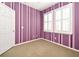 A bedroom features vibrant striped walls, plush carpeting, and dual windows with shutter-style blinds at 1027 Banks Rose St, Celebration, FL 34747