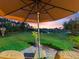 Beautiful backyard view of the lake with patio furniture under a large umbrella overlooking a sunset sky at 1233 Cambria Bnd, Kissimmee, FL 34759