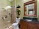 Bathroom features glass shower, granite countertop, wood cabinets, and stacked decorative towels at 1233 Cambria Bnd, Kissimmee, FL 34759