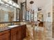 Large bathroom featuring dual sinks, granite counters, a garden tub, and a tiled floor at 1233 Cambria Bnd, Kissimmee, FL 34759