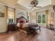A cozy main bedroom features tray ceilings, wood floors, two large windows and a decorative ceiling fan at 1233 Cambria Bnd, Kissimmee, FL 34759