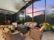 Large covered patio with plush seating and a stunning sunset view through screened windows at 1233 Cambria Bnd, Kissimmee, FL 34759