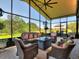 Inviting sunroom with wicker furniture, a gas fire pit, and panoramic views of the lush green landscape at 1233 Cambria Bnd, Kissimmee, FL 34759