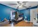 This bedroom features blue walls, hardwood floors, ceiling fan, bunkbed, and curtained window at 1437 Swift Ct, Kissimmee, FL 34759