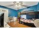 A bedroom with bright blue walls and hardwood floors featuring a bunkbed and ceiling fan at 1437 Swift Ct, Kissimmee, FL 34759