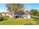 Rear exterior shot of a single-story home with solar panels, a well-manicured lawn and mature trees at 1437 Swift Ct, Kissimmee, FL 34759