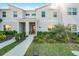 Charming front view of modern townhome, featuring manicured landscaping, a brick-accented porch, and ample sunlight at 2569 Reading Trl, Kissimmee, FL 34746