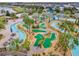 An aerial view of a mini golf course with a winding lazy river and palm trees in a lush community at 2569 Reading Trl, Kissimmee, FL 34746