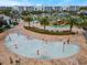 Aerial view of a modern splash pad with colorful water features near a resort-style pool and seating area at 2569 Reading Trl, Kissimmee, FL 34746