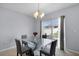 Dining room with modern chandelier, glass-top table, gray chairs, and sliding glass doors at 260 Willow Bend Dr, Davenport, FL 33897