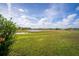 Expansive backyard view with lush green lawn, a pond and blue skies and clouds at 2718 Nakina Ct, Orlando, FL 32837