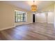 Spacious living room with wood-look flooring, a large window letting in natural light, and a stylish modern light fixture at 2931 Chilton St, Deltona, FL 32738