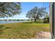Large backyard featuring lush green grass and waterfront views of the adjacent lake at 4061 Flowering Peach Ln, St Cloud, FL 34772