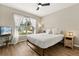 Bright bedroom featuring a ceiling fan, hardwood floors, and a large window with sheer curtains at 407 Reserve Dr, Davenport, FL 33896