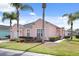Charming pink home featuring a well-manicured lawn and tropical landscaping with palm trees at 407 Reserve Dr, Davenport, FL 33896