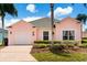 Lovely pink single-story home with lush landscaping, a green lawn, and a well-maintained front yard at 407 Reserve Dr, Davenport, FL 33896