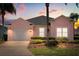 Charming pink single-story home featuring lush landscaping and a well-maintained front yard at dusk at 407 Reserve Dr, Davenport, FL 33896