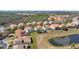 Aerial view of a home overlooking a pond, featuring a screen-enclosed pool and Mediterranean-style tile roof at 478 Chelsea Ave, Davenport, FL 33837