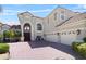 Elegant two-story home featuring a brick driveway, arched entry, and a three-car garage at 478 Chelsea Ave, Davenport, FL 33837