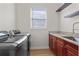 Bright laundry room featuring a gray washer and dryer set, wooden floors and cabinets with granite countertops at 478 Chelsea Ave, Davenport, FL 33837