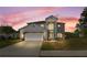 Exterior of two-story home at dusk, featuring a two car garage, and decorative shrubbery at 5516 Willow Bend Trl, Kissimmee, FL 34758