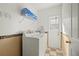 Bright laundry room with stacked washer and dryer, storage shelf, and access to the outside at 5516 Willow Bend Trl, Kissimmee, FL 34758