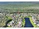 Wide aerial view of a neighborhood with a pond and lush green spaces surrounded by trees at 722 Portofino Dr, Kissimmee, FL 34759