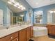 Well-lit bathroom with a soaking tub, dual vanities, and a large mirror, offering a spa-like experience at 722 Portofino Dr, Kissimmee, FL 34759