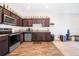 Functional kitchen with wood-look flooring, dark wood cabinets, granite counters, and modern appliances at 728 Madison Dr, Davenport, FL 33837