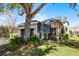 Exterior view of home with screened-in patio and lush landscaping, including mature trees at 7412 Soiree Way, Reunion, FL 34747