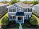 Inviting two-story home featuring a well-manicured lawn, dark shutters, and a covered entryway at 7412 Soiree Way, Reunion, FL 34747