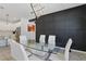 Elegant dining area featuring modern lighting, a glass-top table, and an accent wall, adjacent to the kitchen at 7793 Clove Hitch Way, Orlando, FL 32832