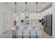 Modern white kitchen with stainless steel appliances, marble countertops, pendant lighting, and seating at the island at 7793 Clove Hitch Way, Orlando, FL 32832