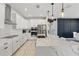 Stylish kitchen featuring stainless steel appliances, white cabinetry, a spacious island, and pendant lighting at 7793 Clove Hitch Way, Orlando, FL 32832