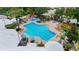 Aerial view of a resort-style community pool with umbrellas, beach chairs, and splash-pad at 8204 Fan Palm Way, Kissimmee, FL 34747