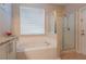 Bright bathroom with a garden tub with tile surround and glass enclosed walk-in shower at 8204 Fan Palm Way, Kissimmee, FL 34747
