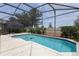 A private screened-in pool with a textured deck and mature landscaping at 8204 Fan Palm Way, Kissimmee, FL 34747