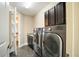 Well-equipped laundry room with dark cabinets, washer, and dryer with view to the bathroom at 13041 Gabor Ave, Orlando, FL 32827
