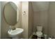 Shot of a powder room, showing a pedestal sink with an oval mirror and a toilet at 13041 Gabor Ave, Orlando, FL 32827