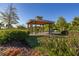 A gazebo provides shade for a picnic table among the lush landscape with flowers and greenery in this community park at 14321 Wabasso Loop, Winter Garden, FL 34787