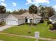 Well-kept single story home with a spacious green lawn, palm tree, and a two-car garage at 1718 Golfview Dr, Kissimmee, FL 34746