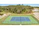 Aerial view of a tennis court bordered by ponds and a lush green forest in a peaceful setting at 1785 Coriander Dr, Kissimmee, FL 34759