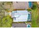 Aerial view of the house's roof, backyard, screened-in pool, lawn, and surrounding greenery at 2105 Mallory Cir, Haines City, FL 33844