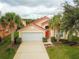 Inviting single-Gathering home featuring a two-car garage and a lush lawn with mature landscaping at 215 Cordova Ave, Davenport, FL 33897
