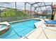 Beautiful screened-in pool and jacuzzi area surrounded by lush greenery and lounge chairs at 215 Cordova Ave, Davenport, FL 33897